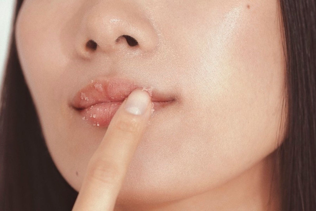 Close-up of a woman gently touching her lips with her finger. Her lips appear smooth and hydrated, emphasizing a soft and natural beauty look.