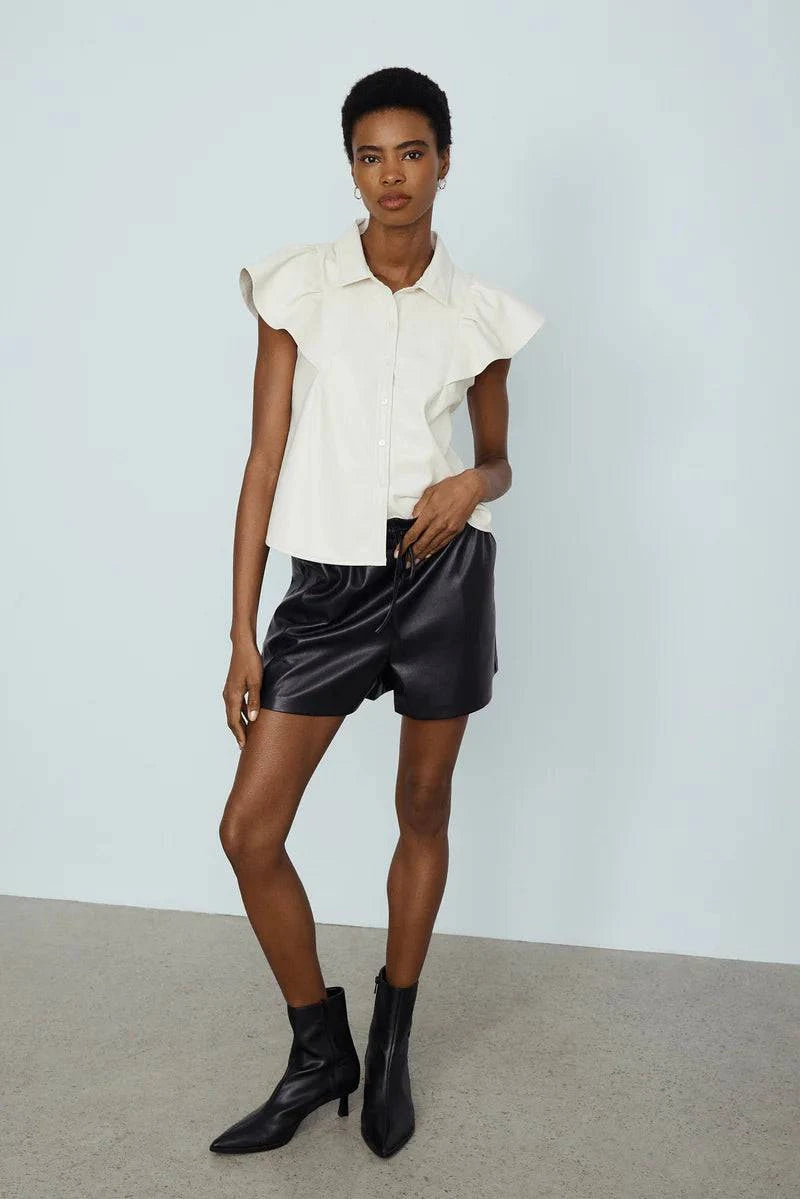 Model wearing the white Nessah faux leather top by Melissa Nepton with black shorts, a chic casual look in Victoria, B.C.