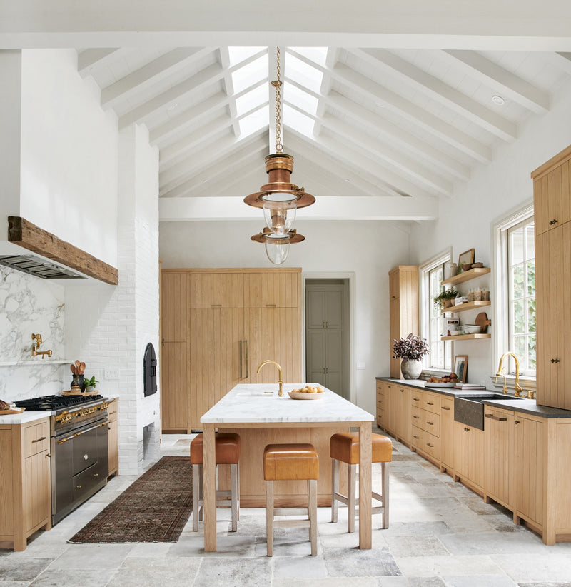 A view from a stylish family room into a modern, open-concept kitchen with natural tones, wood accents, and curated decor from "Made for Living."