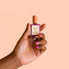 Hand holding another pink Bkind Nail Polish bottle, showcasing a soft and feminine shade."