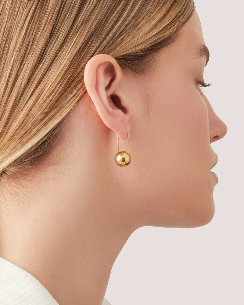  Model wearing Celeste Earrings in gold, showcasing a sleek, minimalist drop design.