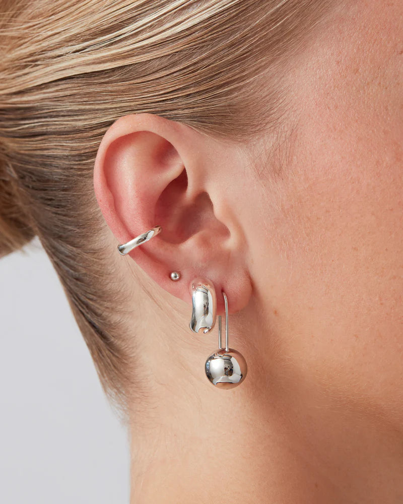 Model wearing Celeste Earrings in high-polish silver, a modern and elegant statement piece.