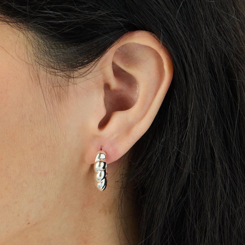 A model wearing the Croissant Earrings in Silver by Foxy Originals, a Canadian, woman-owned brand. A stylish, Parisian-inspired statement piece.