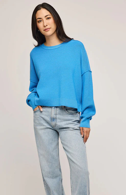 Front view of the Echo Sweater in Capri blue, showcasing exposed seams and side slits.