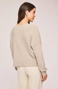 Back view of the Echo Sweater in Sand, showcasing the side slits and exposed seams.