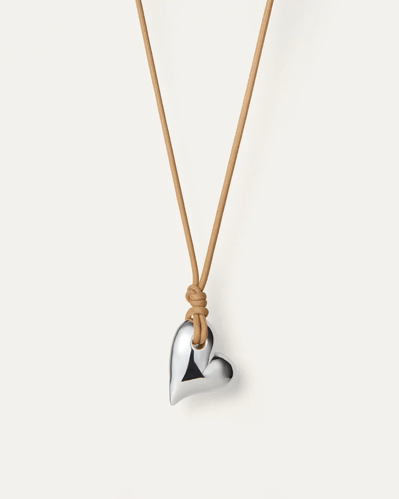 The Art Heart on a String Necklace by Jenny Bird in silver, featuring a heart-shaped pendant made from silver-tone glass, hanging from an adjustable sand-colored cord made from recycled polyester.