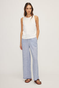 Woman wearing Kelsi Satin Mixed Media Sleeveless Top in white, styled with striped pants.