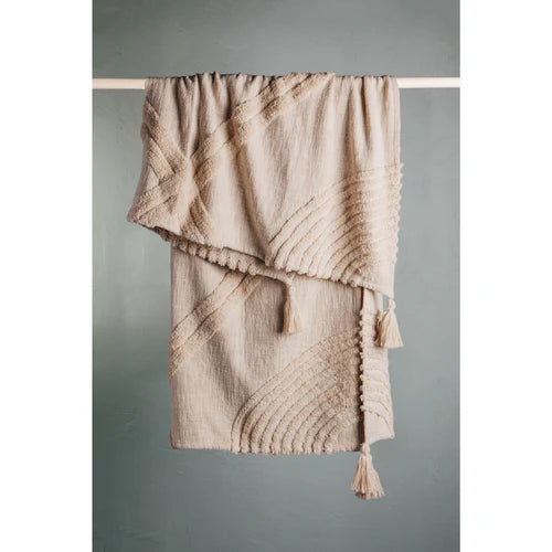 The Niva Throw blanket draped over a bar, highlighting its soft texture, patterns, and decorative fringe or tassels.