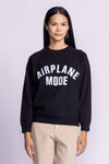 Front view of the Pink Martini Catching Flights Sweater, featuring a raglan cut and "Airplane Mode" text patch.