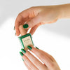 Hand holding Bkind Nail Polish in a green bottle, a fresh and bold shade for your nails.