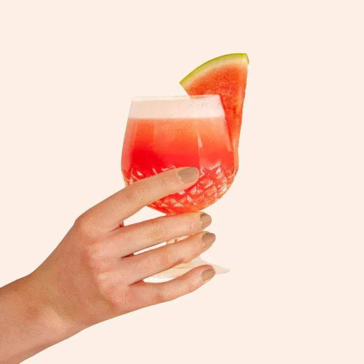 Hand holding a drink with nails painted in Bkind Nail Polish, showing off a chic manicure.