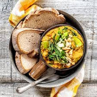 A prepped meal from the "Delicious and Doable" cookbook by Charmaine Broughton, served in a bowl with a side of bread, showcasing a delicious and healthy dish.