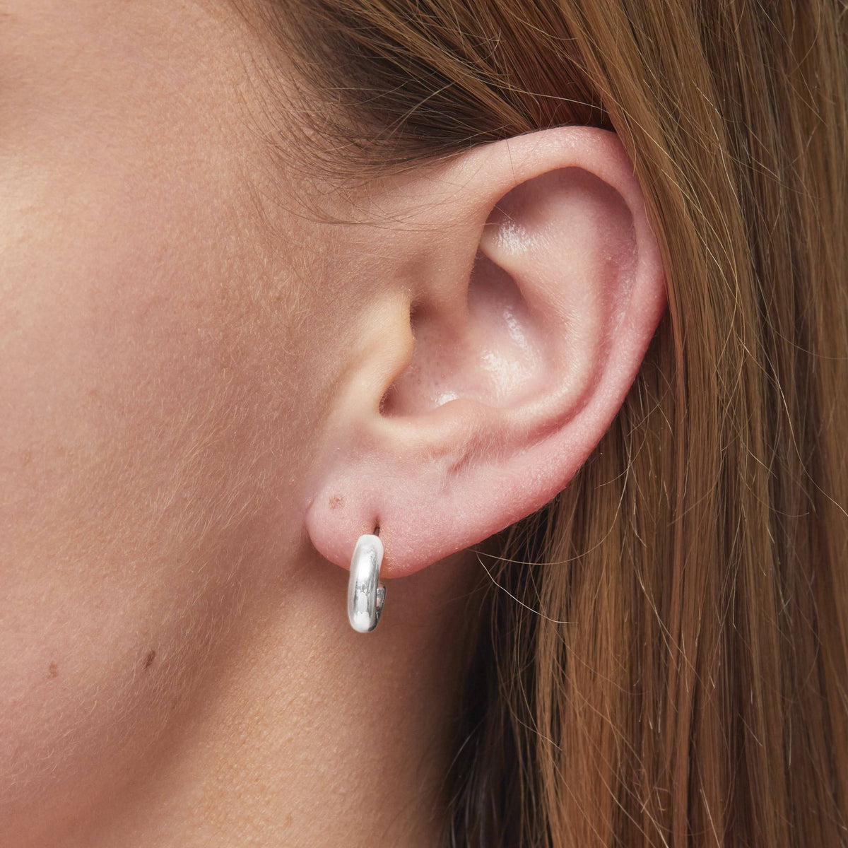 Close-up of a model wearing Foxy Originals Petite Hoops in silver, showcasing their lightweight and stylish design.