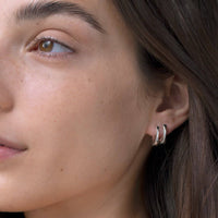 Teeni Tony by Jenny Bird silver huggie earrings on model, showcasing elegant ear stack.